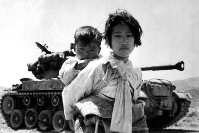 Mulher carrega criança em meio aos combates na Guerra da Coréia